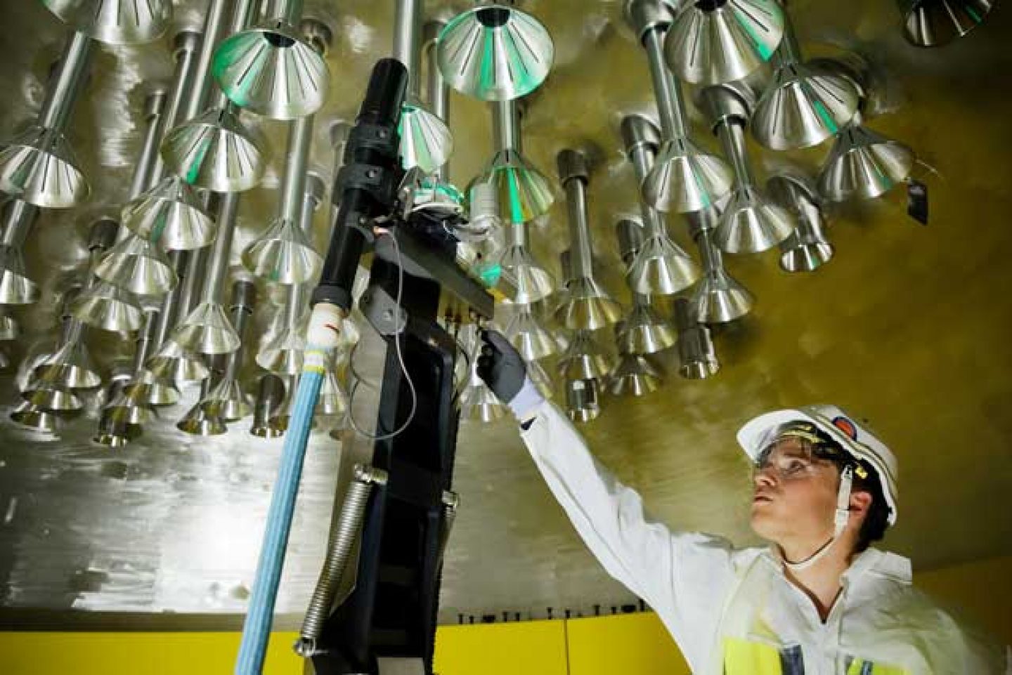 Worker inspecting welds on pressure-retaining parts housing the control-rod drive mechanisms