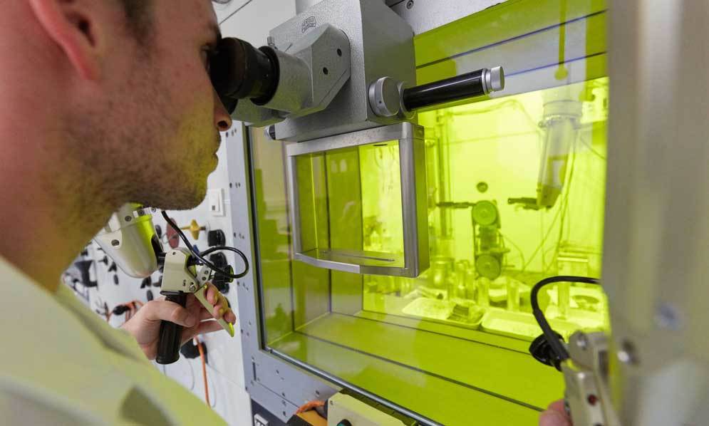 Scientifique analysant des matériaux au microscope dans une cellule chaude